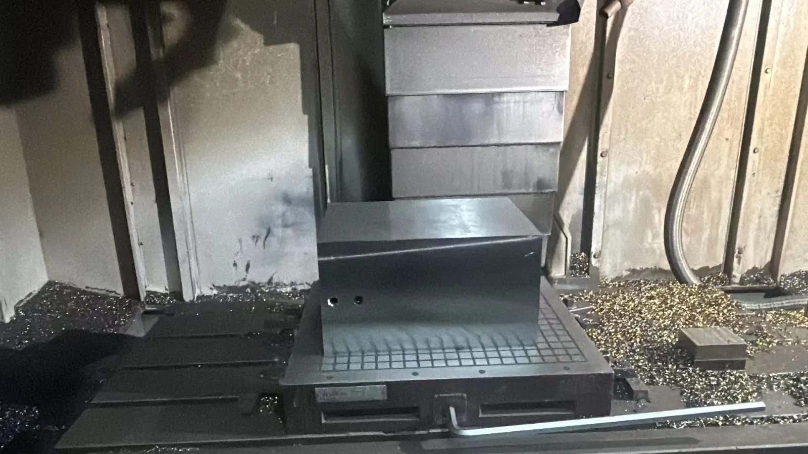 A rough steel mould block clamped on a magnetic table, ready for machining, with metal chips around it