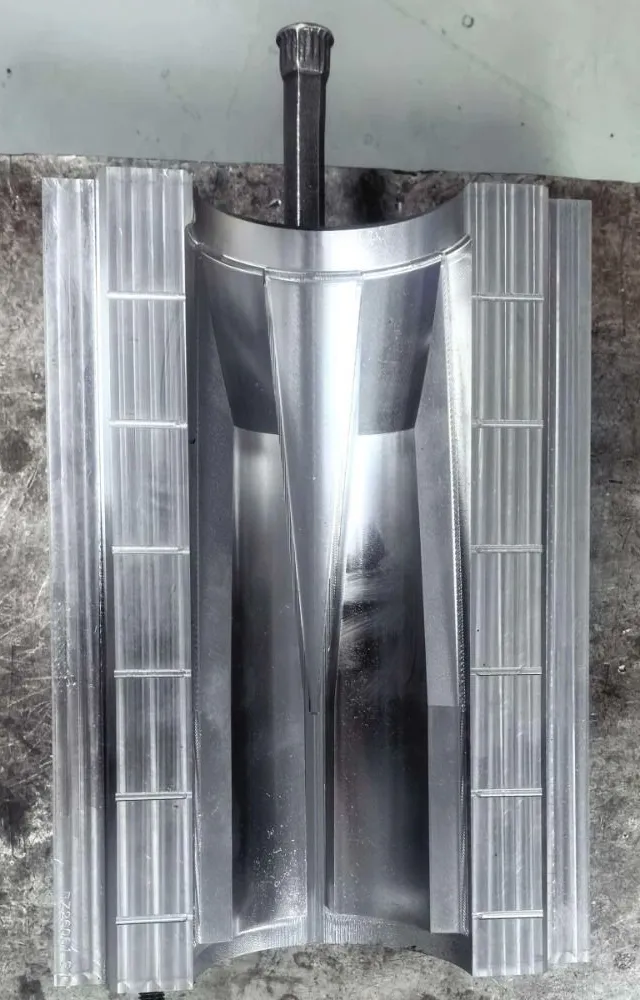 The polished mould half on a steel table, its cavity bright and smooth, with a lifting bar fitted at one end