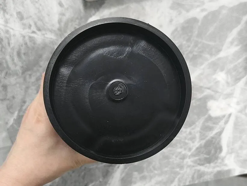 The closed end of a moulded sleeve held in a hand, with the small gate mark at the centre