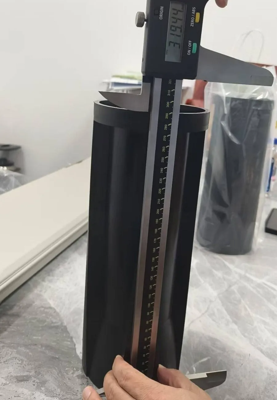 A sample sleeve standing on a table while a large digital calliper measures its length