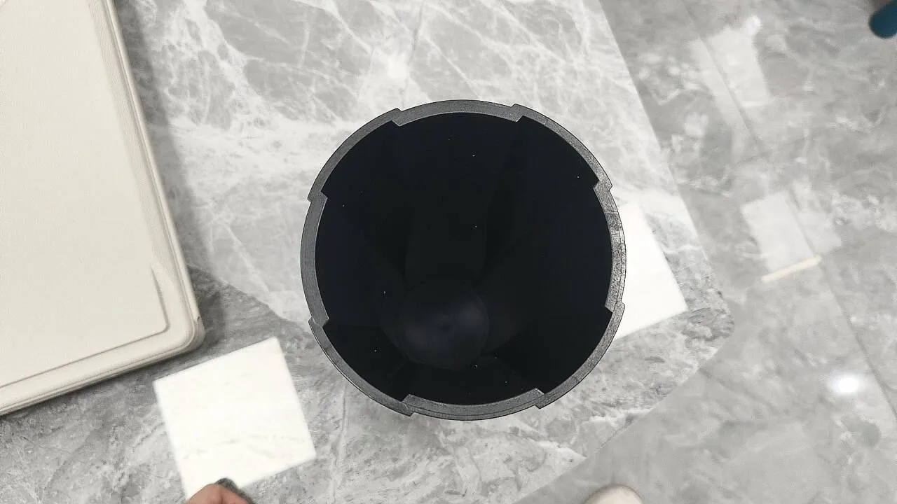 Looking into the open end of a moulded sleeve on a grey marble table, with the slots around its rim