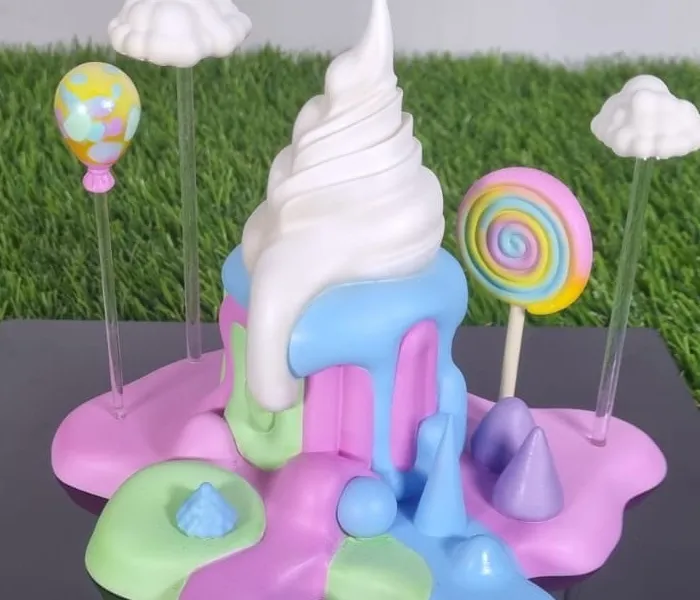 Close-up of the pearl-white swirl melting over blue, pink and mint drips, with the spotted balloon, the rainbow lollipop and two clouds on clear rods