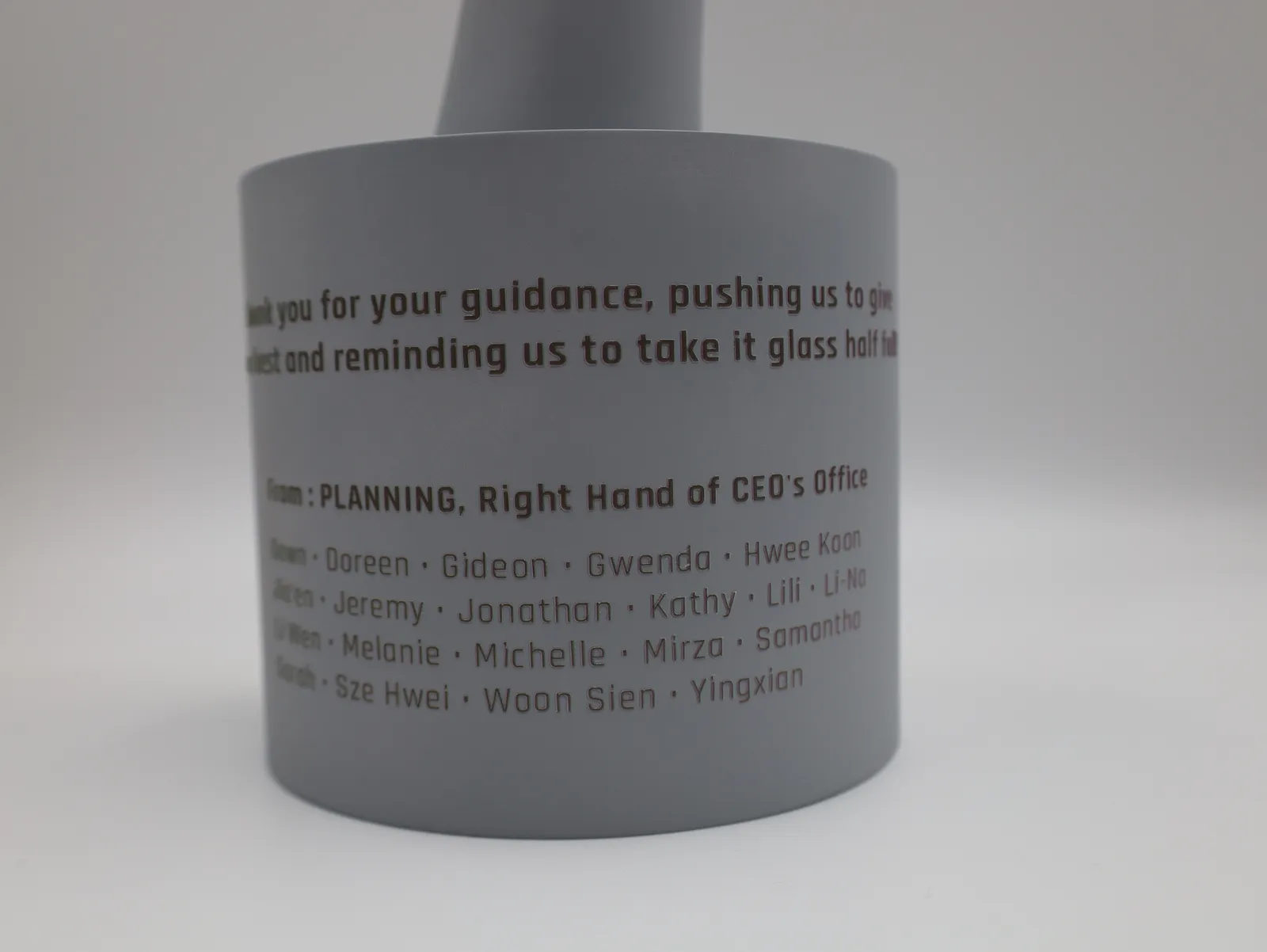 The round grey base with the thank-you message, the line From PLANNING, Right Hand of CEO's Office, and the team's first names printed below