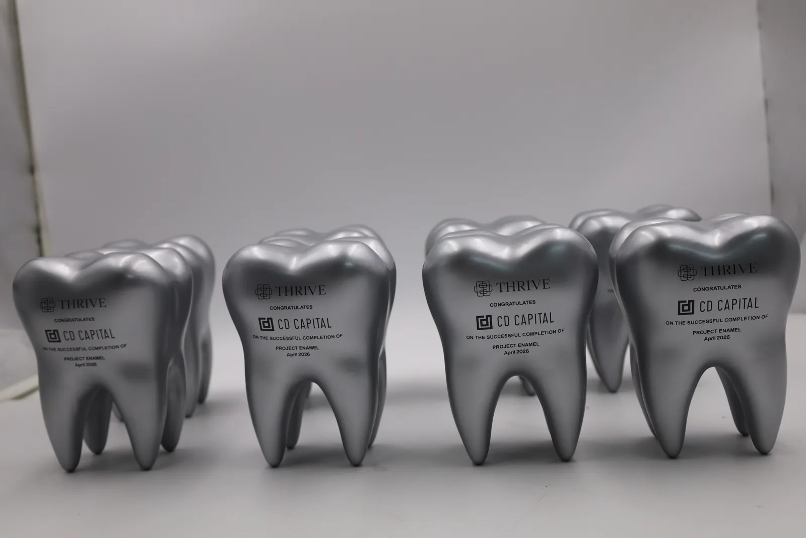 All eight silver tooth trophies lined up in pairs, each with the same black printed logos and message