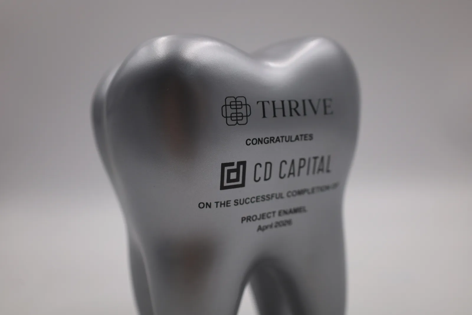 Close up of the black UV-printed Thrive and CD Capital logos on the silver painted surface