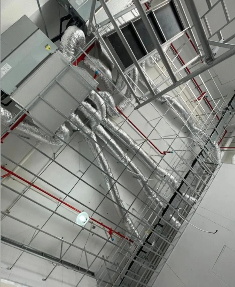 Looking up at the showroom's open ceiling before the installation: ducts, pipes and a steel grid