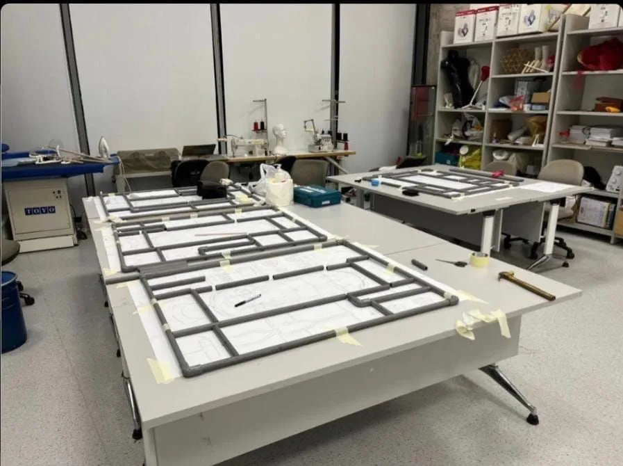 The grey pipe frames of the kits laid out on long tables in a studio