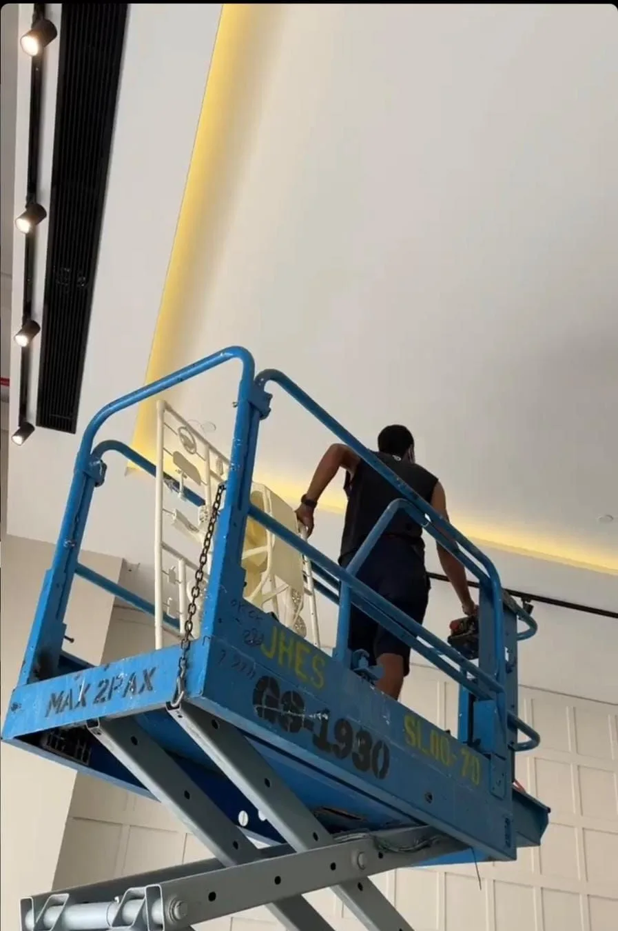 An installer on a scissor lift hanging a car kit under the showroom ceiling