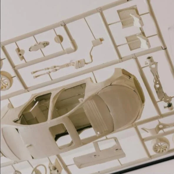Looking up at a hanging kit: an open car body with its suspension, exhaust and wheels on the frame around it