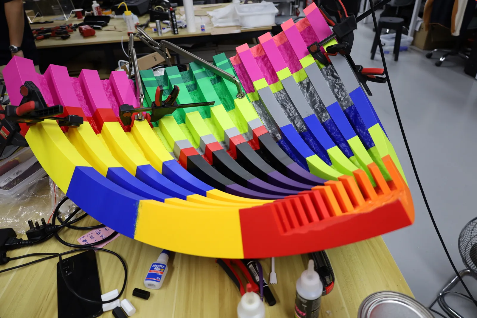 The multicoloured corner mould on a workbench, held in clamps, with bottles of glue beside it