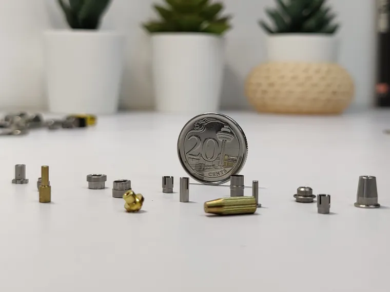 Micro CNC machined metal parts beside a 20-cent coin