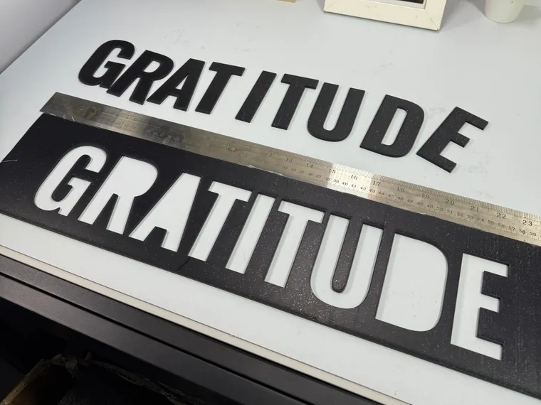 Laser-cut GRATITUDE lettering with its cut stencil panel