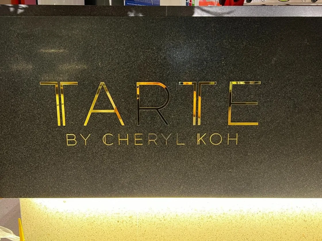 Gold mirror-finish Tarte by Cheryl Koh sign on a dark granite panel