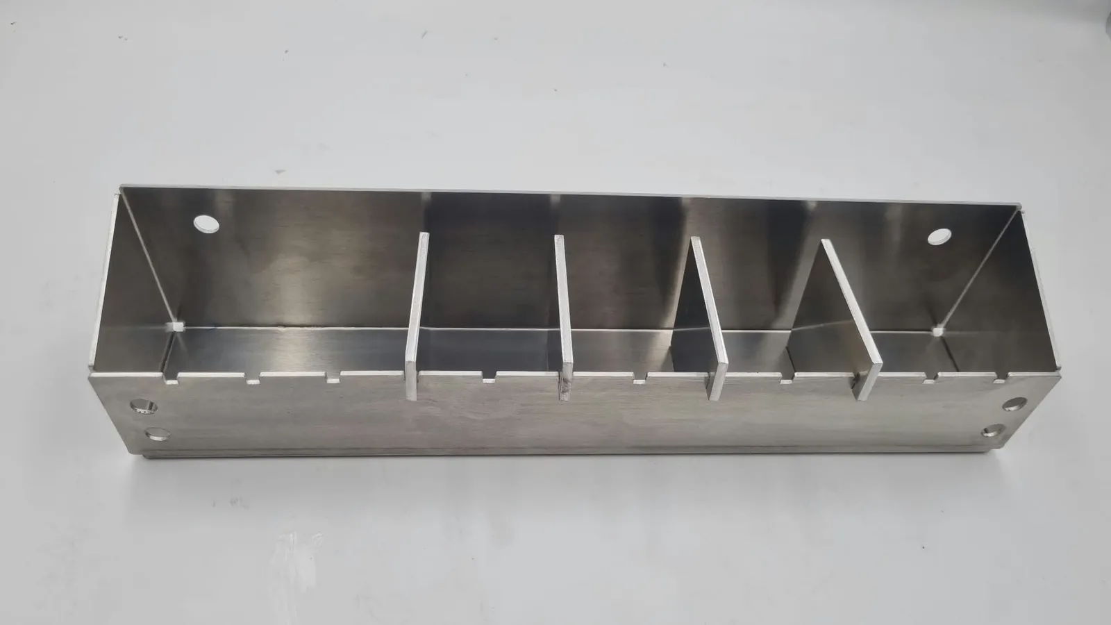 The same aluminium tray seen from the front, its walls folded up from the base and the four dividers standing in a row