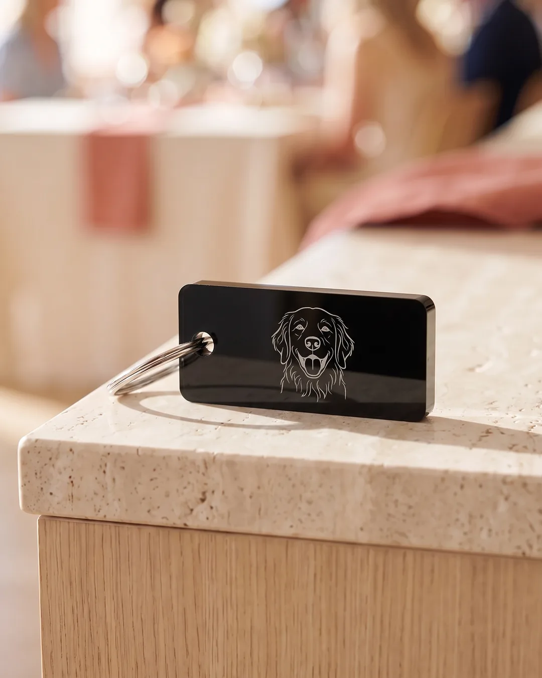A black acrylic keychain engraved with a fine line portrait of a golden retriever in frosted white