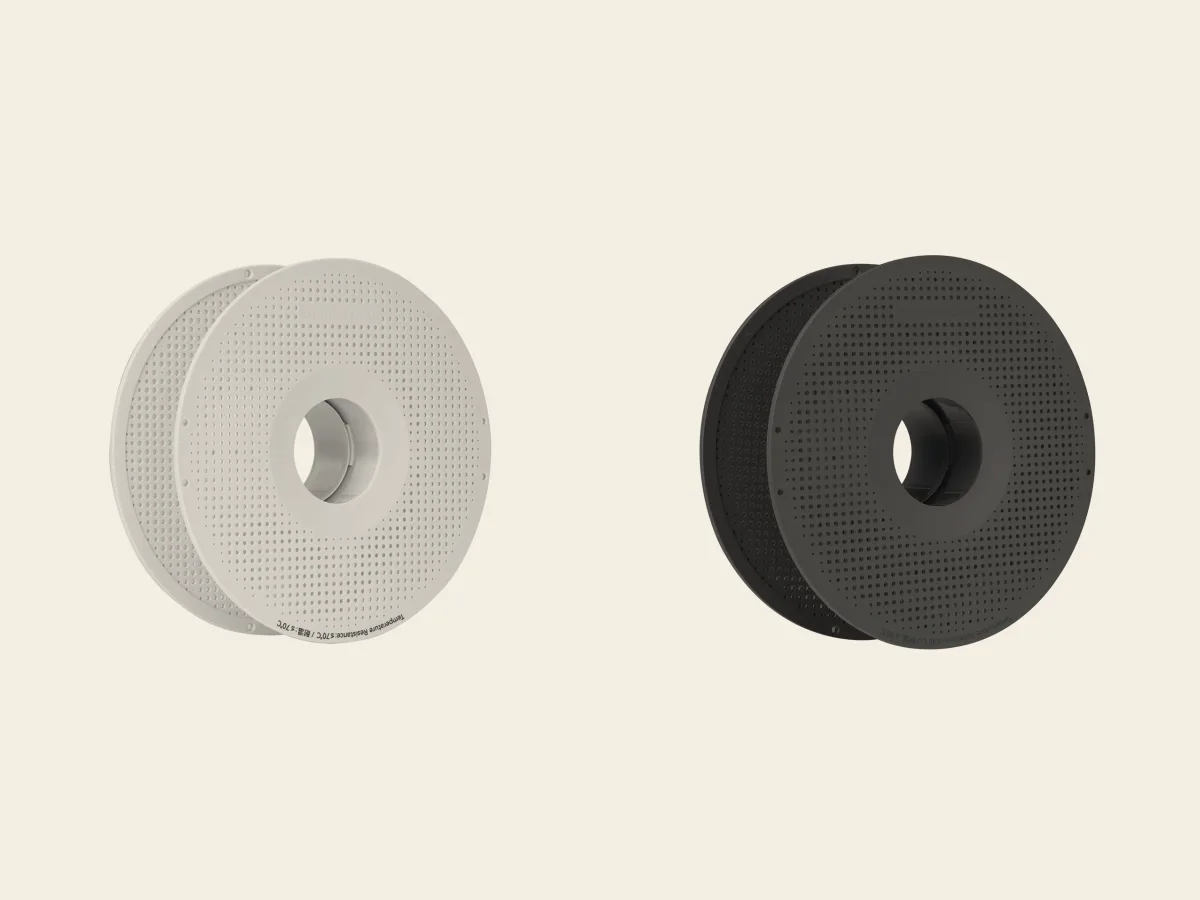 The white standard Bambu reusable spool beside the dark high-temperature version